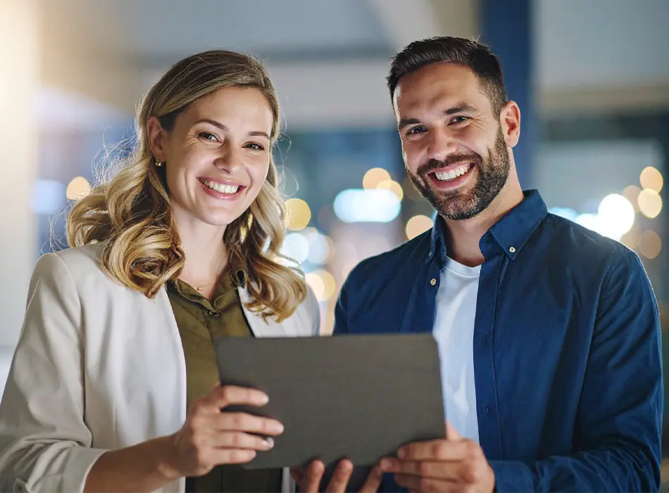 Deux employés souriant de la firme de comptable LGMC qui tient un ordinateur portable dans ses mains.